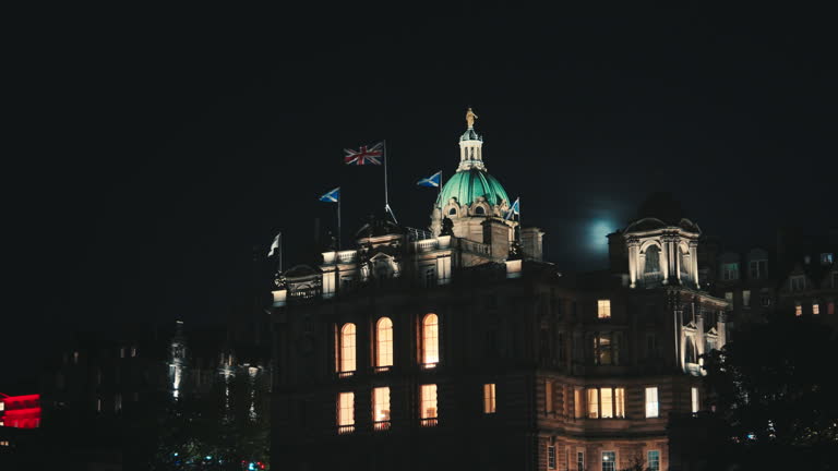 United Kingdom National UK flag with Scotland Flag over the architectural dome of historic on the Mound at nighttime in Edinburgh Old town, Scotland, United Kingdom
