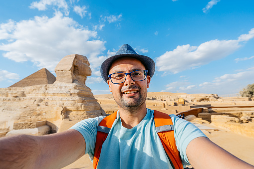 Handsome young man taking selfies in front of the Great Sphinx Of Giza in Cairo, Egypt.