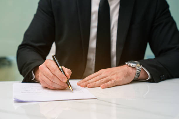 istock Close-up of a person's hand stamping with approved stamp on certificate document at desk. 2150805455