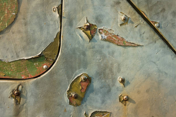Detail of an old camouflage surface with exfoliated paint  and rivets on military equipment. Military background