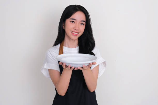 istock An Asian woman wearing apron smiling happy while holding empty dinning plate 2150806263