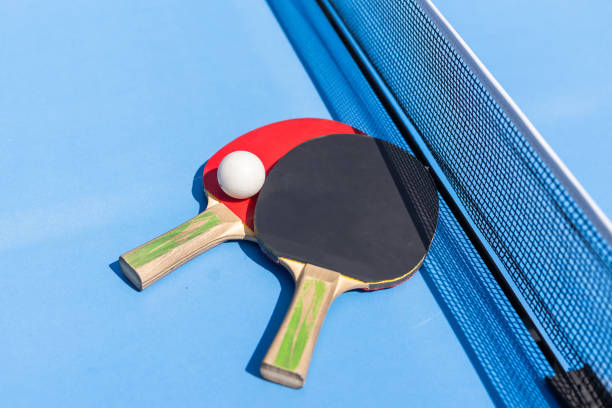 istock Two table tennis or ping pong rackets and ball on blue table with net 2150807904