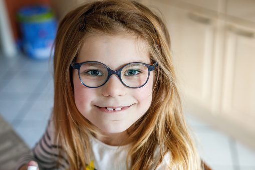 Close-up portrait of a cute little girl with eye glasses. Happy smiling school child with eyeglasses looking at the camera. Childhood concept.