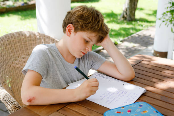 istock Hard-working sad school kid boy making homework during quarantine time from corona pandemic disease. Upset tired child on home schooling in coronavirus covid time, schools closed. 2150808273