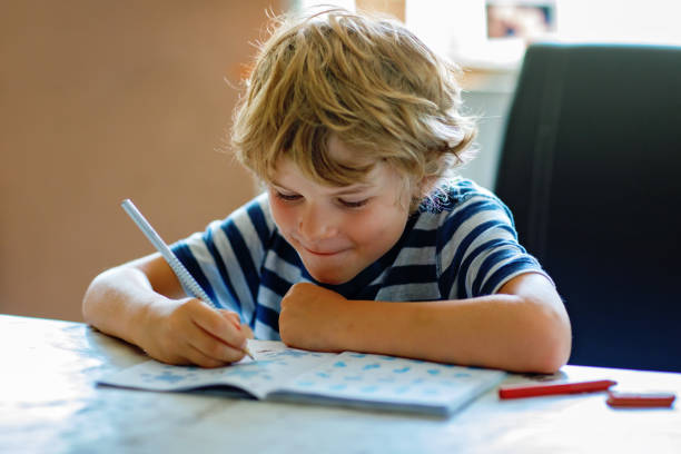 istock Portrait of happy boy doing homework in kitchen at home. Elementary school studing writing and learning. Smiling child. 2150808296
