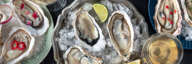 istock Oysters on ice panorama, with various toppings and white wine 2150810631