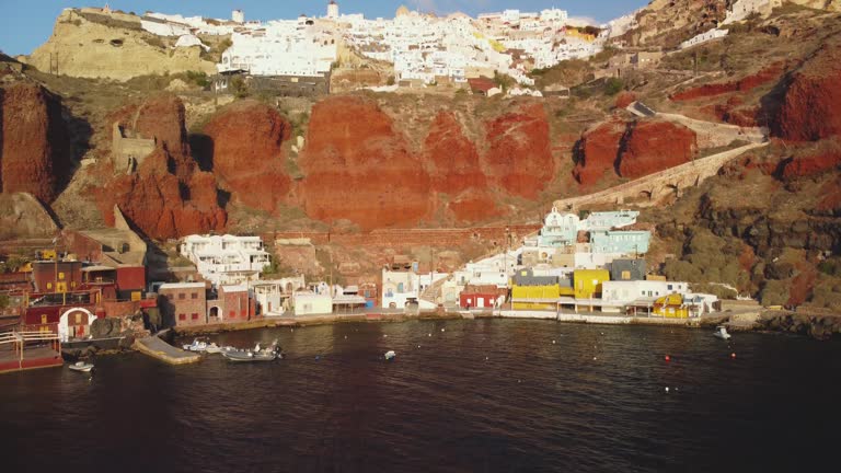 Santorini Greece, AMOUDI BAY Wide Shot,  Red VOLCANIC ROCK Hillside. Fishing Village Port Below Oia on the Greek Island.