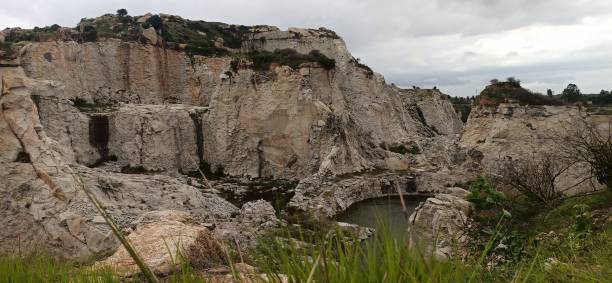istock a serene, pristine setting featuring a green lake, a rocky cliff, lush vegetation, and a clouded sky. 2150816797