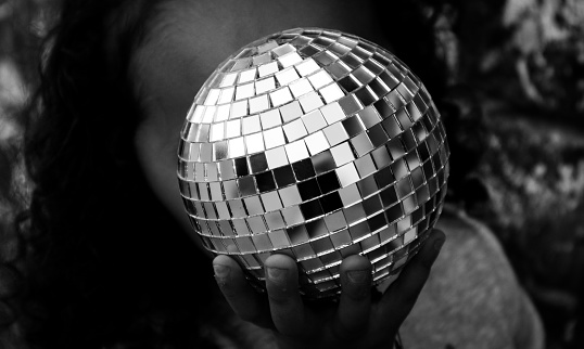 a girl holding a disco ball in front of her face
