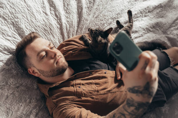 istock Man laying at the bed with his cat and making selfie 2150817295