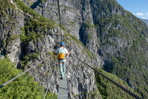 istock Hiker Crossing a Mountain Ridge on a Suspension Bridge 2150817475