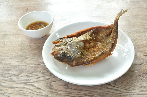 deep fried black-banded trevally fish on plate dipping spicy chili sauce