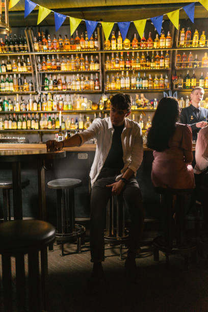 istock Young guy stretches hand to glass in trendy restaurant 2150820772
