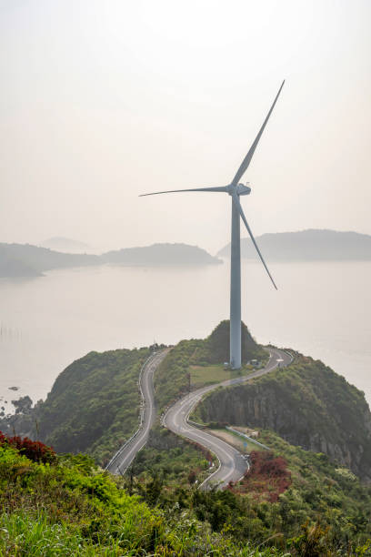Turbines next to a curved asphalt road by the sea