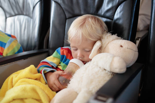 Child in airplane. Kid in air plane sitting in window seat. Flight entertainment for kids. Traveling with young children. Kids fly and travel. Family summer vacation. Little boy with toy in airplane.
