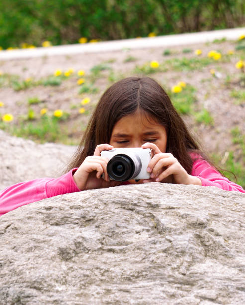 Girl photographing with camera on rock