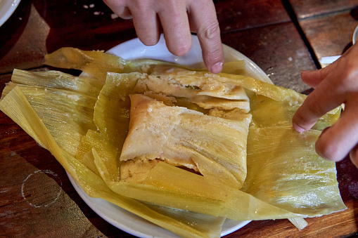 hand unwrapping a tamale in a restaurant in Jujuy, Argentina.