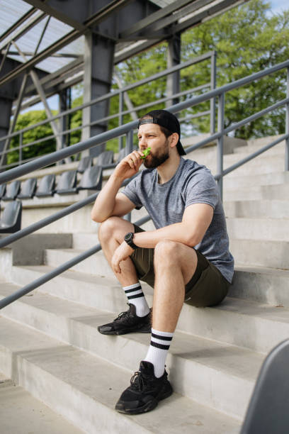 istock The man eats a protein bar at the stadium stairs after training 2150825938