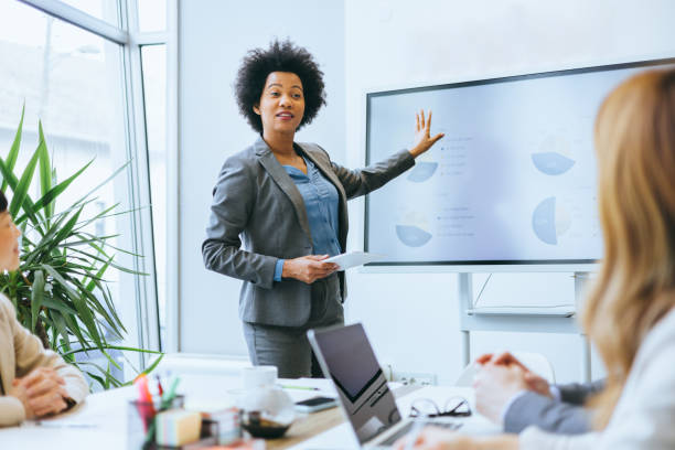 Businesswoman gesturing towards presentation screen