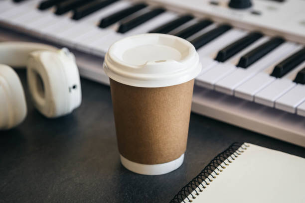 istock Musician workplace table with paper cup and white piano keyboard. 2150826094