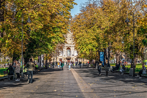 Lviv, Ukraine - November 2, 2023: Sunny autumn day on Svobody Avenue in Lviv. Many people walk along the alley among the golden autumn chestnut trees with the Lviv National Opera in the background