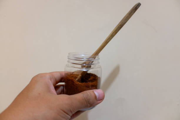 istock A hands holding a jar of coffee and a spoon, with cream background 2150828229