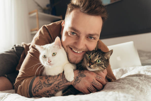 Man embracing with his fluffy domestic cats while laying at the bed