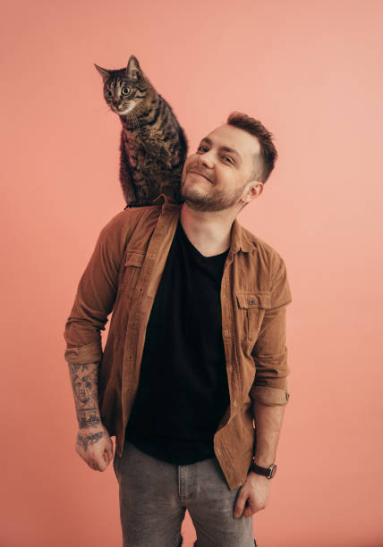 Bearded man smiling while his striped cat sitting at his shoulder