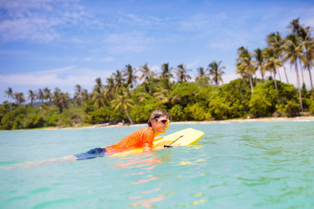 istock Child surfing on tropical beach. Surfer in ocean. 2150829428
