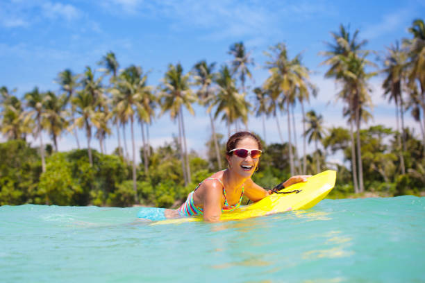 istock Young woman with surf board on tropical beach 2150829574