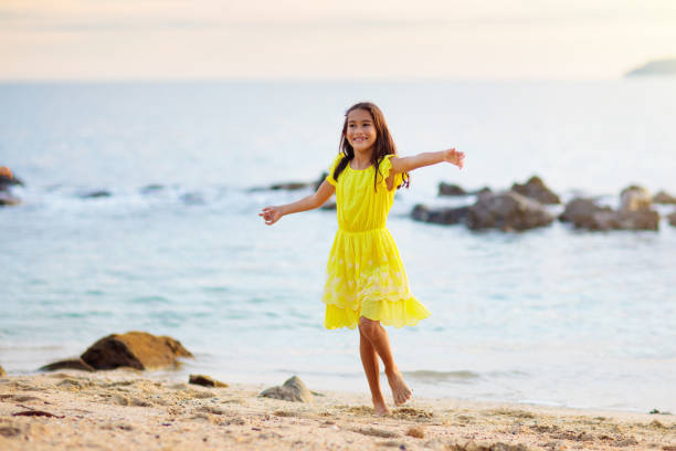 Little girl playing on tropical beach. Children play at sea shore. Water and sand fun. Summer vacation. Travel with kids. Ocean holiday with child. Sunset walk at the beach.