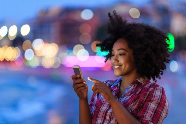 istock Woman with afro using smartphone at night 2150835557