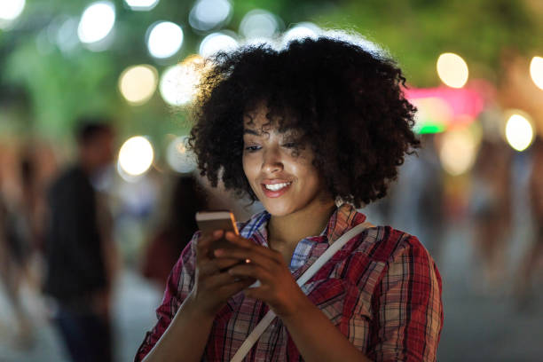 istock Woman browsing phone with city lights 2150835558