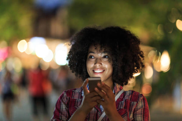 istock Woman browsing phone with city lights 2150835564
