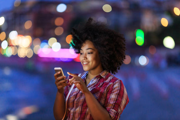 istock Smiling woman using phone with city lights behind 2150835593