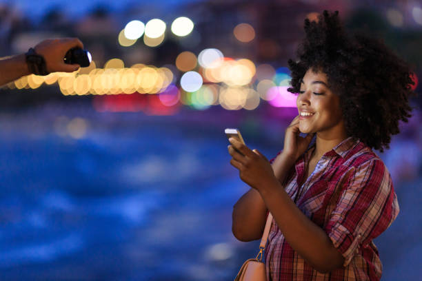 istock Smiling woman using phone with city lights behind 2150835594