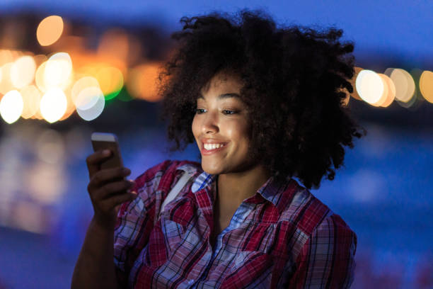 istock Smiling woman using phone with city lights behind 2150835596