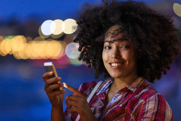 istock Happy woman with phone on urban night backdrop 2150835597