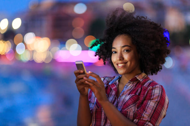 istock Smiling young lady with smartphone in evening 2150835603