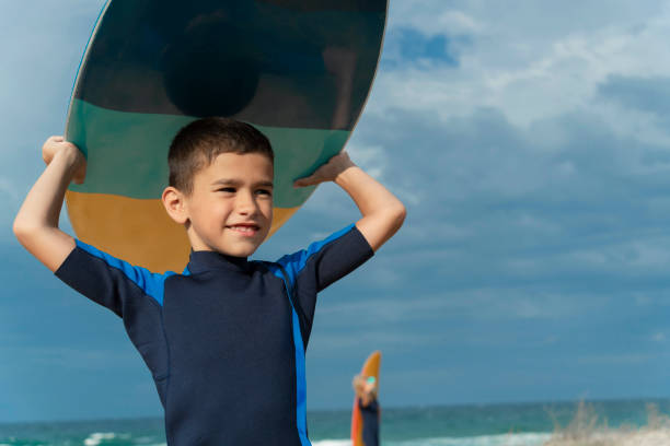 istock Young boy ready to surf with mother nearby 2150836383