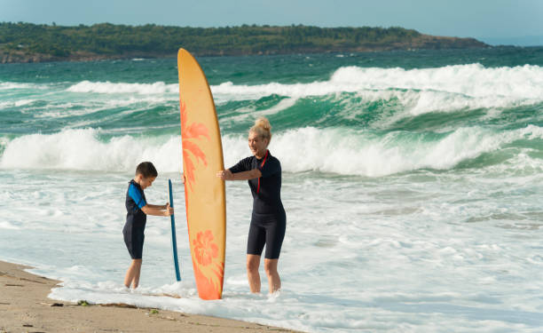 istock Mother teaching son to surf on the beach 2150836423