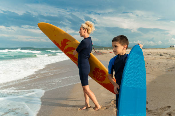 istock Focused boy carrying a surfboard on the beach 2150836441