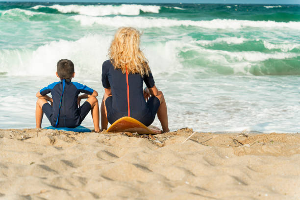istock Mother and son sitting by the sea watching waves 2150836470