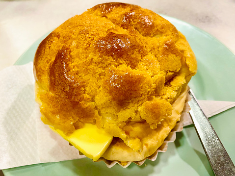 Close-up of fresh pineapple bun with butter on plate in traditional Cha Chaan Teng (Hong Kong Style tea restaurant) setting