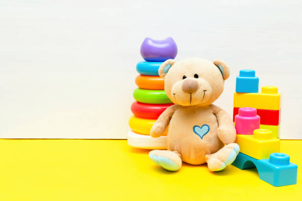 istock teddy bear with colorful pyramid, constructor, toy blocks for children play on white yellow background, baby's childhood development, Educational logic toys for toddler kid's concept, copy space 2150844242