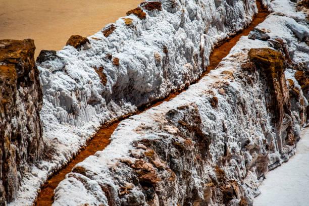 detail of the mountain salt pans with the white of the salt and the brown of the water which is turning into salt with evaporation in Peru in South America