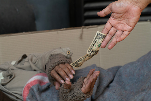 A person is giving a homeless man money.