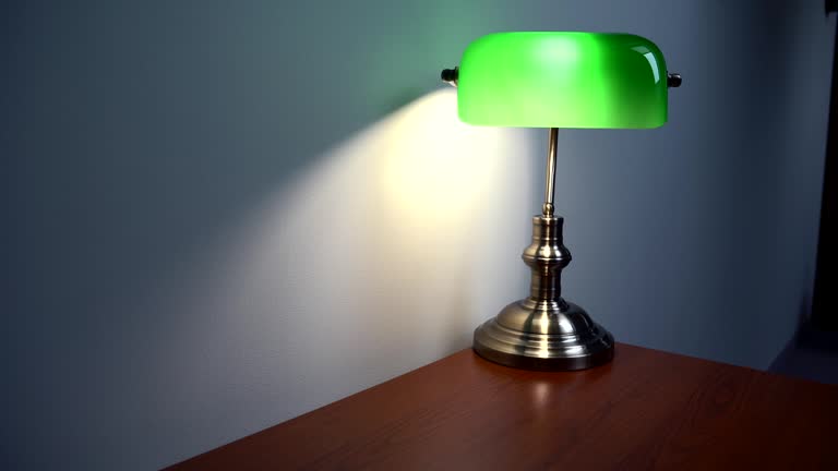 Green Reading Lamp on the brown desk. Slow, steady camera move.