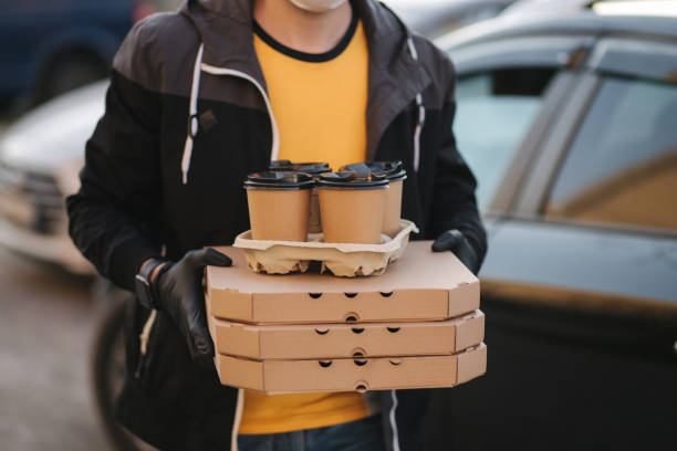 istock Man take order from car. Delivery boy hold pizza and coffe. Delivery service 2150851734