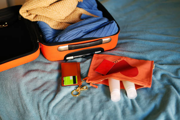 Open orange suitcase with different clothes packed for journey at home